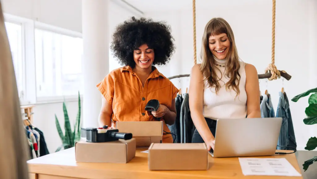 Two women standing looking at a computer working on their small business