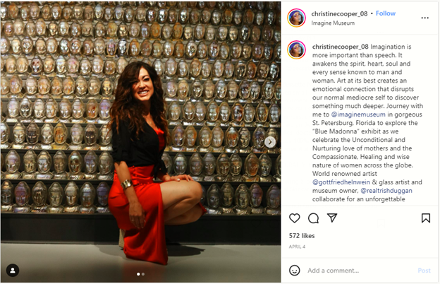 Christine Cooper kneeling in front of dark art display at a museum