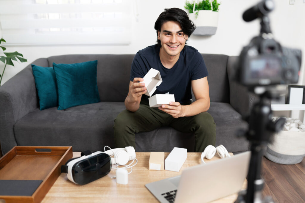Male influencer unboxing a product and recording it using a camera and microphone
