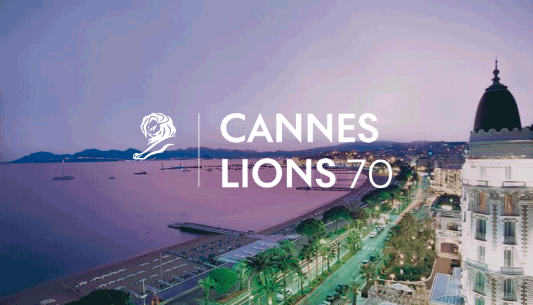Landscape with hotels, houses, the ocean, and mountain range in the south of france with the Cannes Lions 70 logo on top 