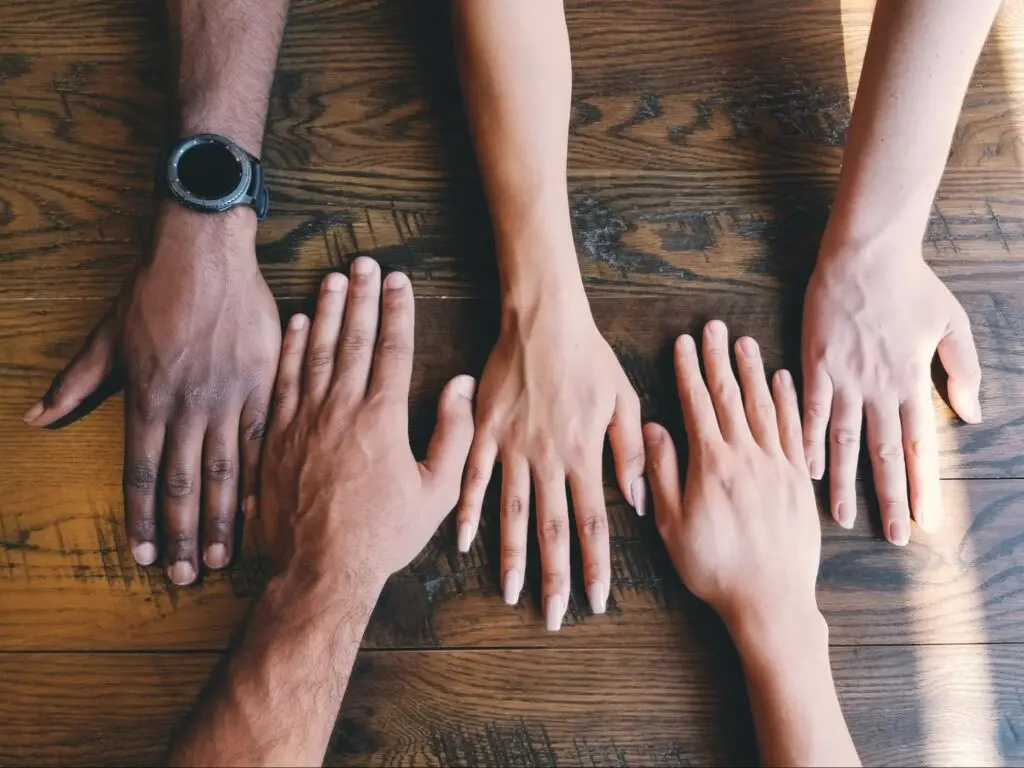 Hands reaching over a wooden table.